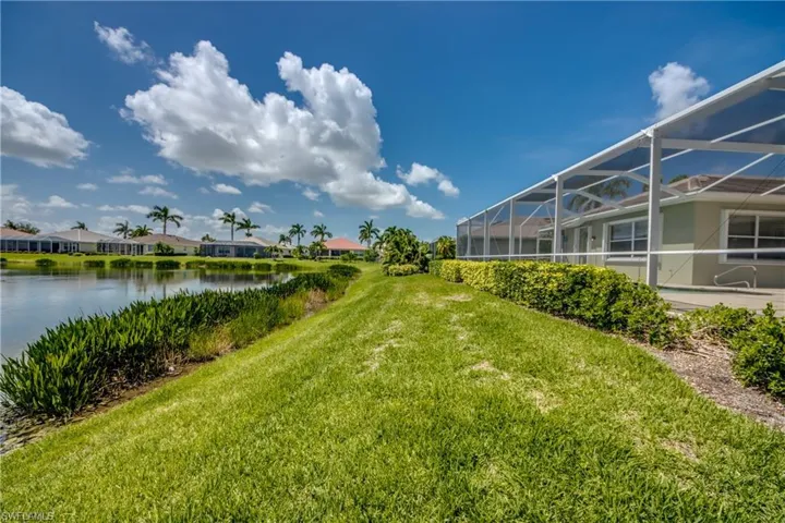 View of green lawn featuring a water view, a lanai, and a residential view