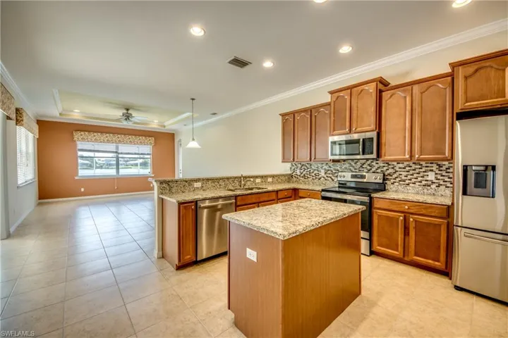 Kitchen featuring stainless steel appliances, a peninsula, backsplash, light stone countertops, and recessed lighting