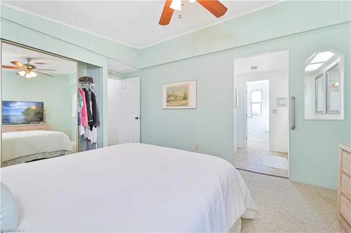 Bedroom with a ceiling fan, light carpet, crown molding, and a closet