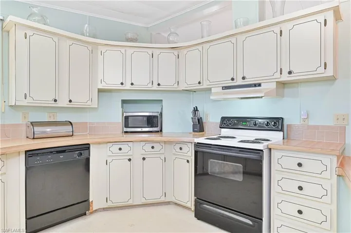 Kitchen with range with electric cooktop, light countertops, black dishwasher, light flooring, and ornamental molding