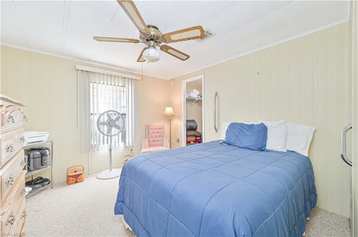 Bedroom featuring a walk in closet, carpet flooring, ceiling fan, and crown molding