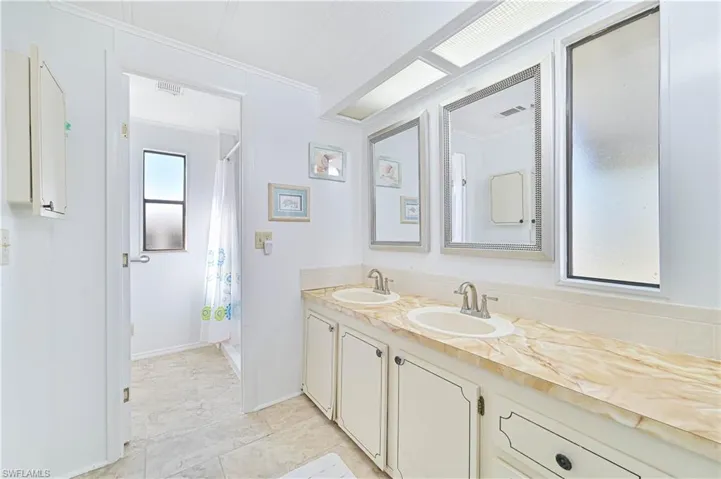 Bathroom with double vanity, a shower with curtain, and crown molding