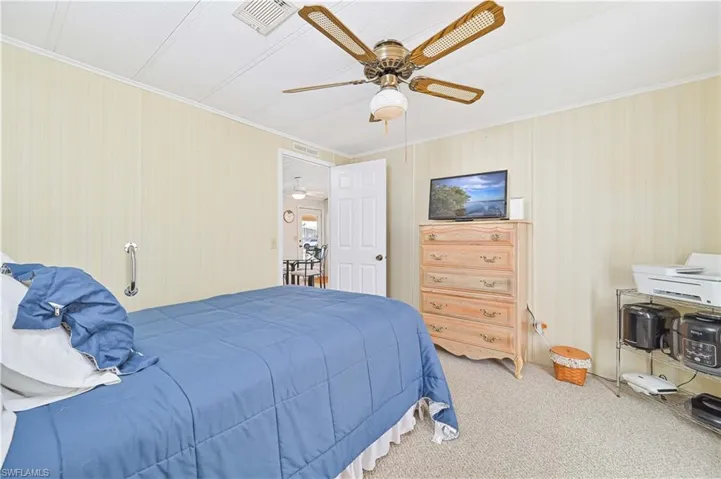 Carpeted bedroom with crown molding, wallpapered walls, and ceiling fan