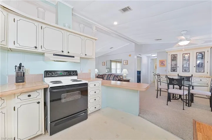 Kitchen with electric range oven, vaulted ceiling, light countertops, ceiling fan, and recessed lighting