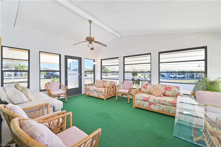 Sunroom with healthy amount of natural light, carpet flooring, and vaulted ceiling with beams