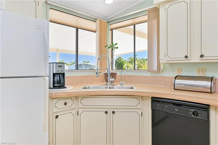 Kitchen with freestanding refrigerator, black dishwasher, plenty of natural light, and light countertops