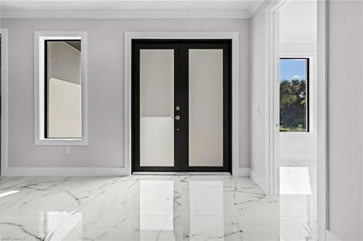 Entrance foyer featuring crown molding and french doors