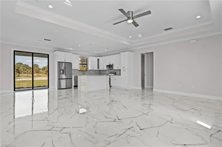 Unfurnished living room featuring crown molding, a raised ceiling, and ceiling fan