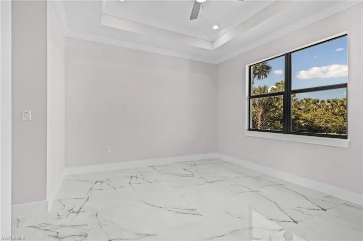 Unfurnished room featuring crown molding, ceiling fan, and a raised ceiling