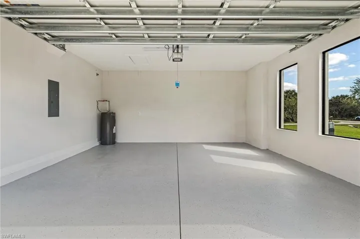 Garage featuring a garage door opener, electric panel, and electric water heater