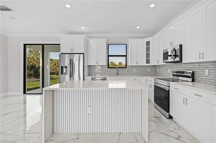 Kitchen with white cabinetry, stainless steel appliances, and a center island