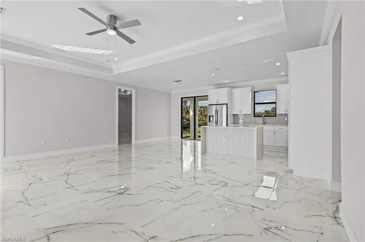 Empty room featuring a raised ceiling, crown molding, and ceiling fan
