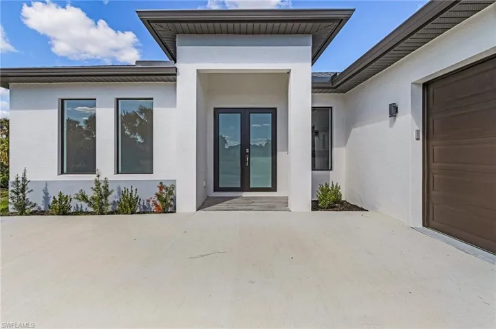 View of exterior entry featuring french doors, a garage, and a patio