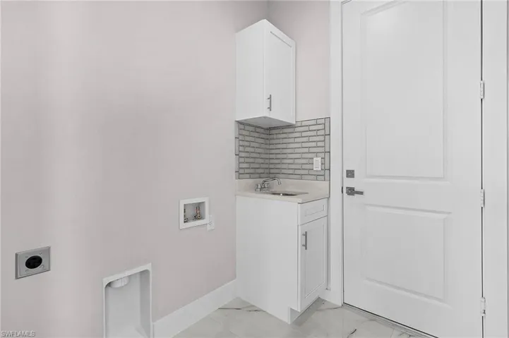 Laundry room with hookup for a washing machine, electric dryer hookup, sink, and cabinets