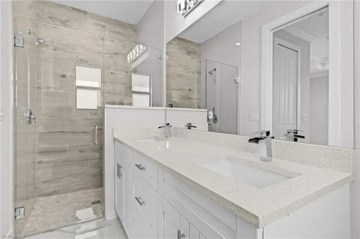 Bathroom featuring ornamental molding, vanity, and an enclosed shower
