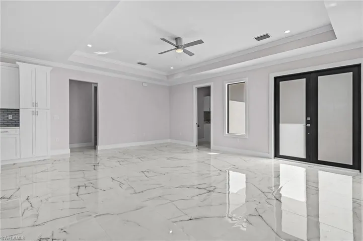 Unfurnished room with a tray ceiling, ornamental molding, french doors, and ceiling fan