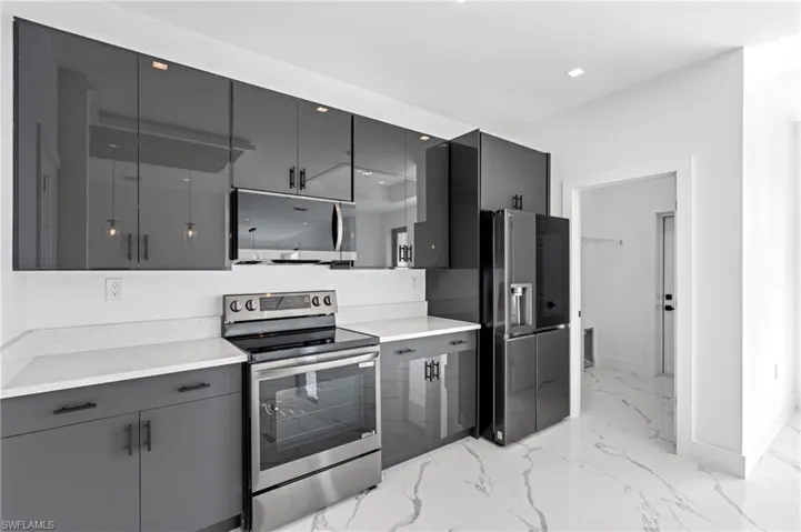 Kitchen with stainless steel appliances, gray cabinetry, modern cabinets, and light marble finish floors