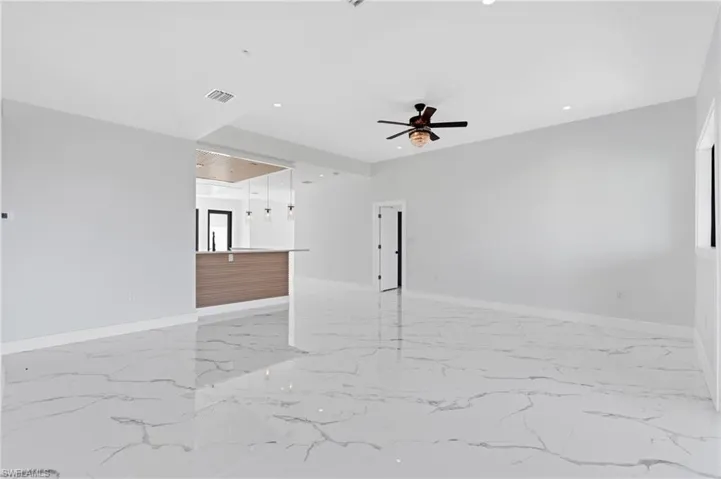 Unfurnished room with ceiling fan, recessed lighting, and light marble finish flooring