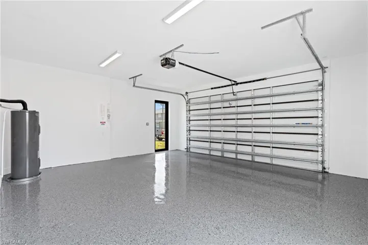 Garage featuring electric water heater and a garage door opener