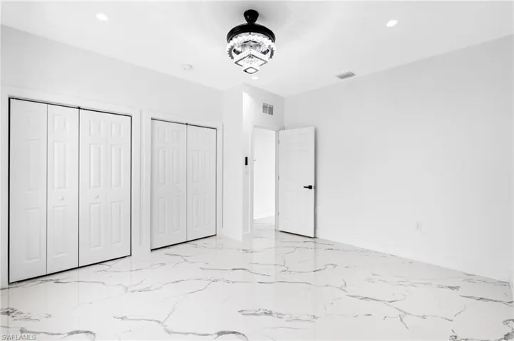 Unfurnished bedroom with multiple closets, recessed lighting, and light marble finish floors