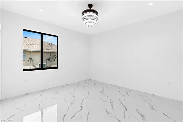 Empty room featuring baseboards and a chandelier