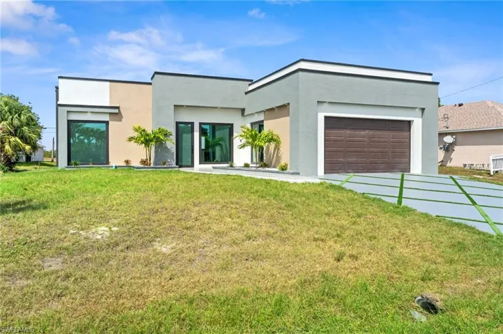 Contemporary home with a front yard, stucco siding, an attached garage, and driveway