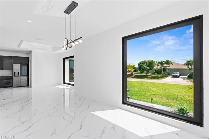 Unfurnished dining area featuring recessed lighting, a tray ceiling, and light marble finish floors