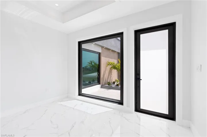 Empty room featuring light marble finish floors, a tray ceiling, and recessed lighting