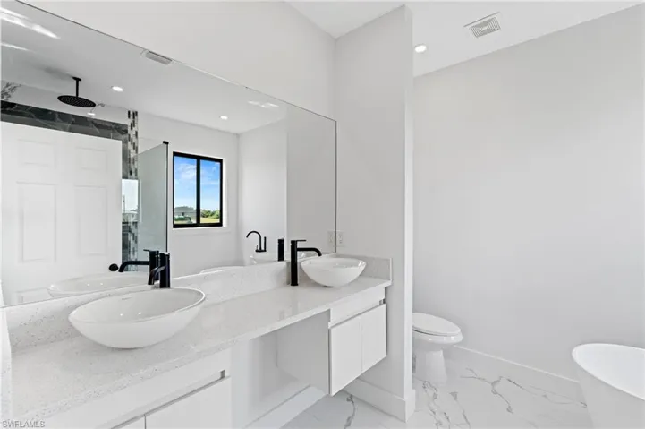 Full bath with a soaking tub, double vanity, a stall shower, recessed lighting, and light marble finish flooring