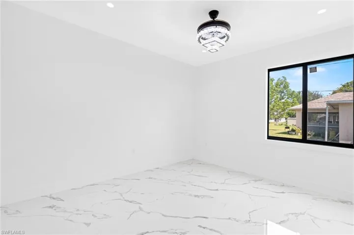 Spare room with light marble finish floors and suspended lighting