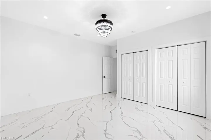 Unfurnished bedroom with multiple closets, light marble finish floors, and recessed lighting