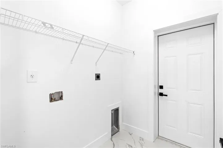 Laundry area with electric dryer hookup, hookup for a washing machine, and light marble finish flooring