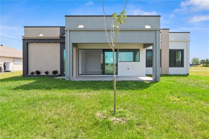 Rear view of property featuring a patio, a lawn, and stucco siding