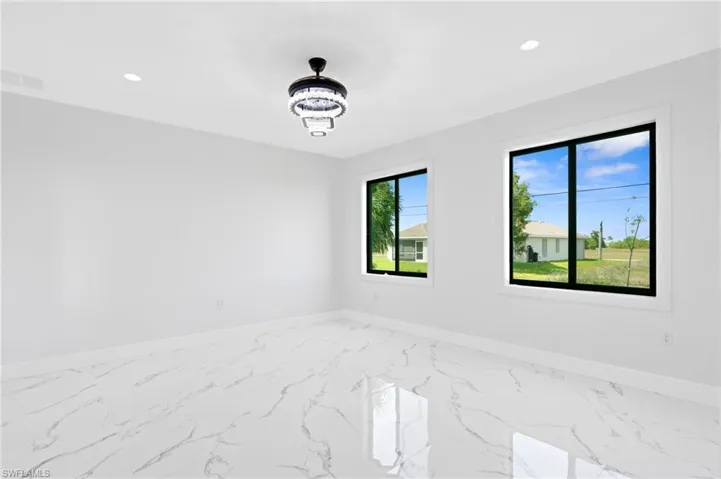 Spare room with light marble finish floors and suspended lighting