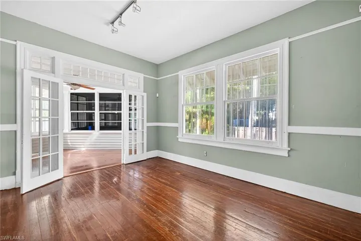 Empty room with dark wood-type flooring, healthy amount of natural light, rail lighting, and a ceiling fan