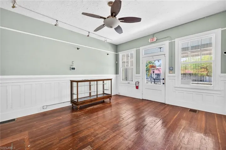Foyer entrance featuring dark wood-style floors, a wainscoted wall, plenty of natural light, a textured ceiling, and rail lighting