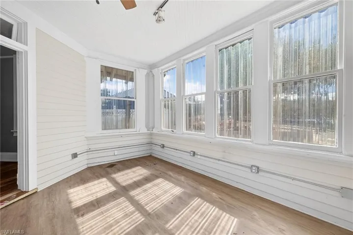 Unfurnished sunroom with wood finished floors and wood walls