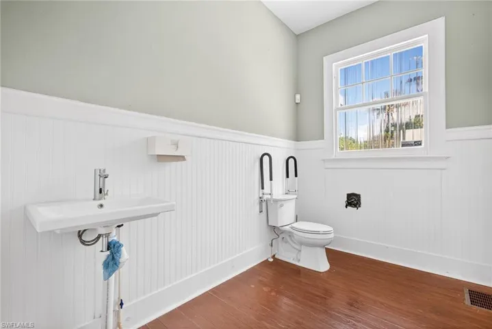 Bathroom with wainscoting and dark wood-type flooring