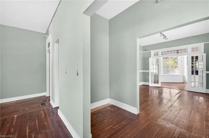 Hall with dark wood-type flooring, french doors, and a high ceiling