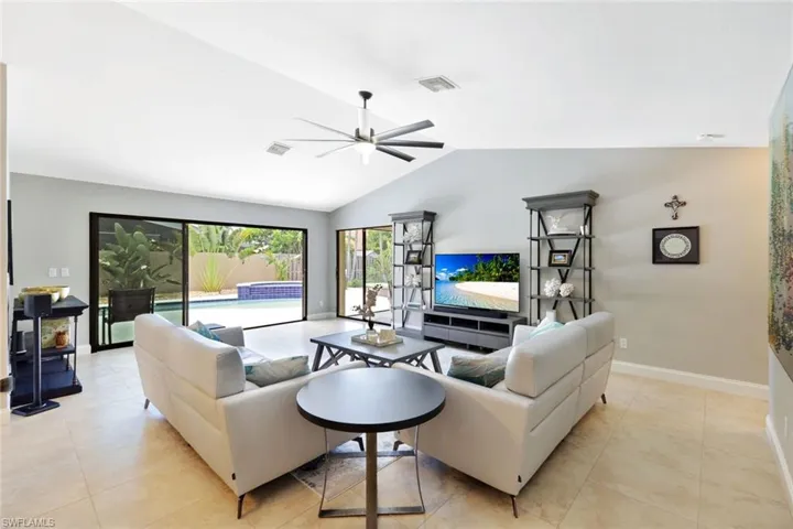 Tiled living room featuring lofted ceiling and ceiling fan