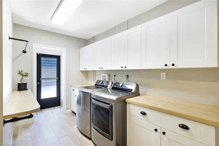 Clothes washing area with cabinets, light hardwood / wood-style floors, and washing machine and dryer
