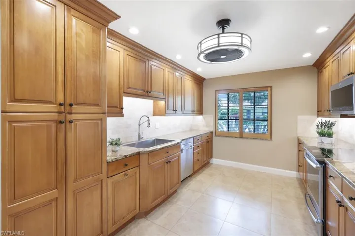 Kitchen with tasteful backsplash, sink, light stone countertops, and appliances with stainless steel finishes