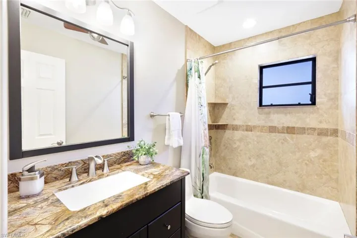 Full bathroom featuring shower / bath combination with curtain, vanity, and toilet