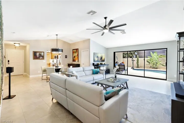 Living room with vaulted ceiling, light tile patterned floors, and ceiling fan