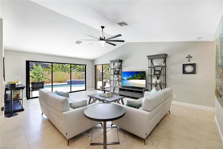 Tiled living room featuring ceiling fan and lofted ceiling