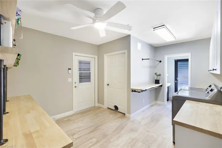Kitchen featuring ceiling fan, washing machine and dryer, and white cabinets