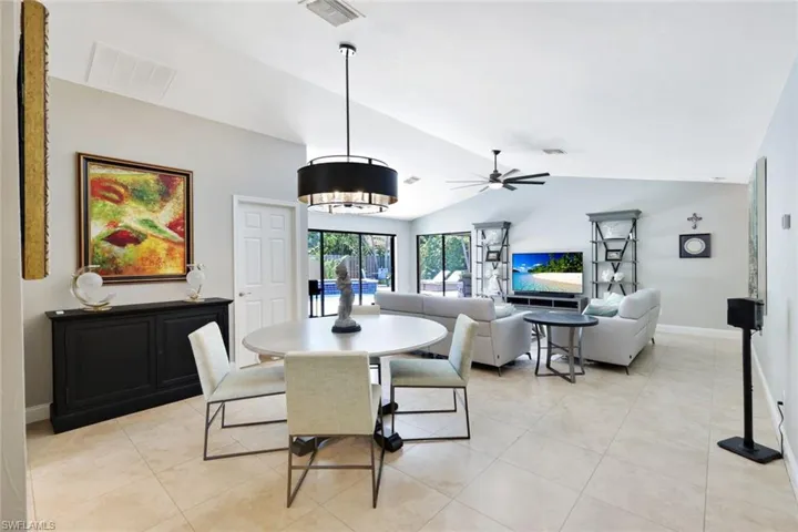 Dining space with vaulted ceiling, light tile patterned floors, and ceiling fan