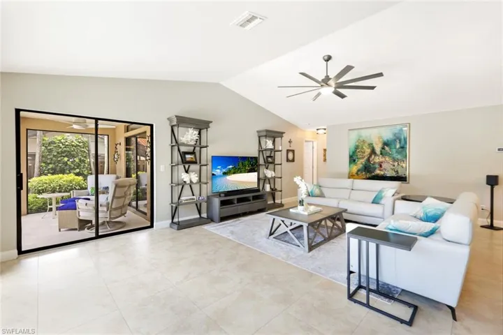 Living room featuring light tile patterned flooring, lofted ceiling, and ceiling fan