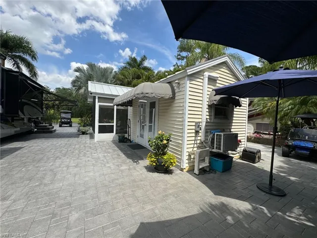 View of side of property featuring cooling unit, an outbuilding, and a patio area