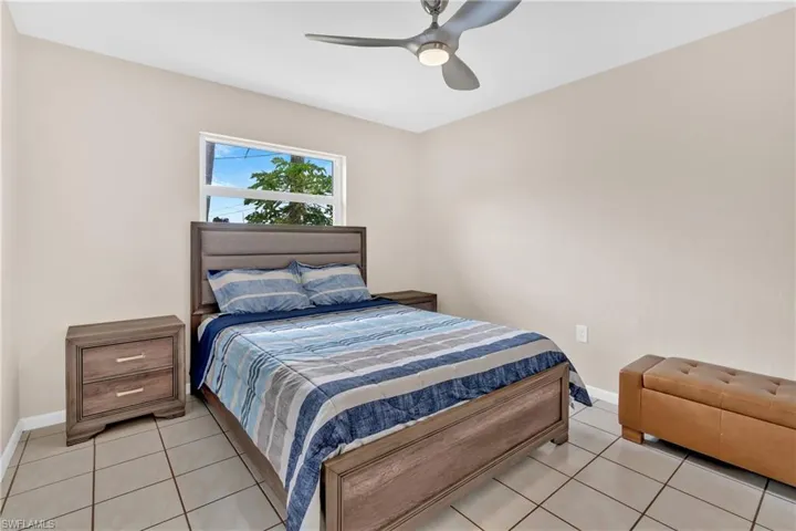 Tiled bedroom with ceiling fan and baseboards
